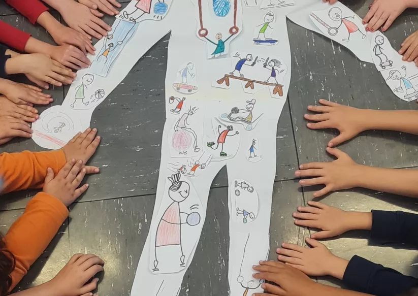 Die Kinder zeigen auf ihre sportlichen Strichmännchen zum Thema: Wir sind in Bewegung.